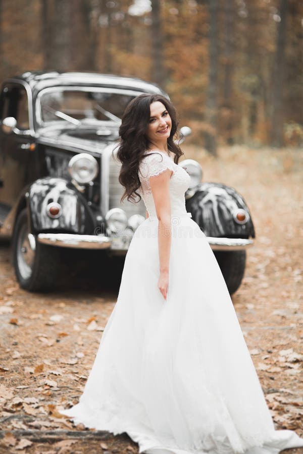 Happy bride in the retro car posing on her weeding day.