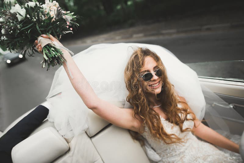 Happy bride in the retro car posing on her weeding day.