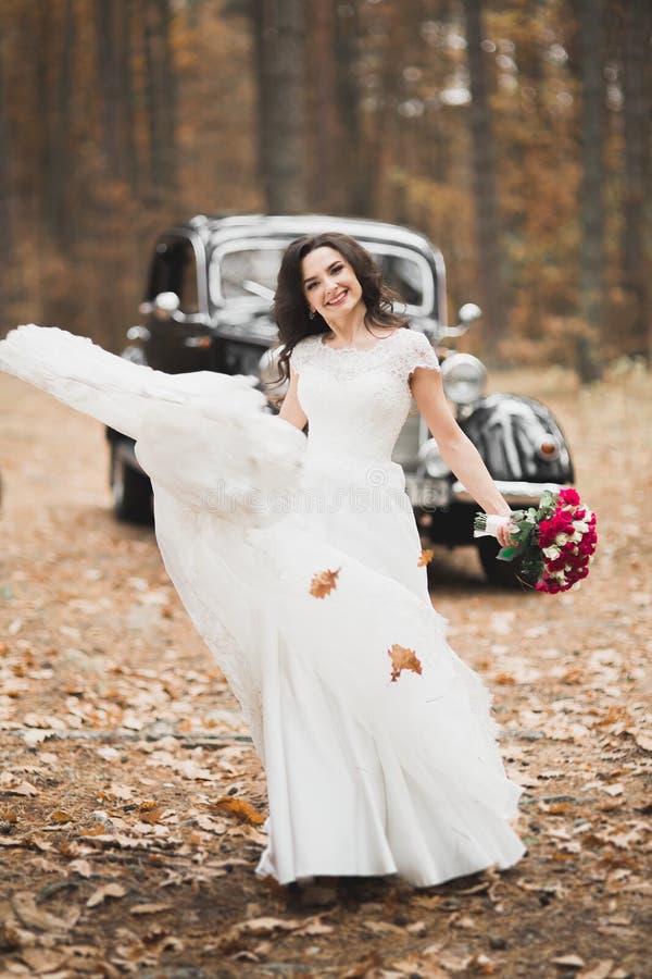 Happy bride in the retro car posing on her weeding day.