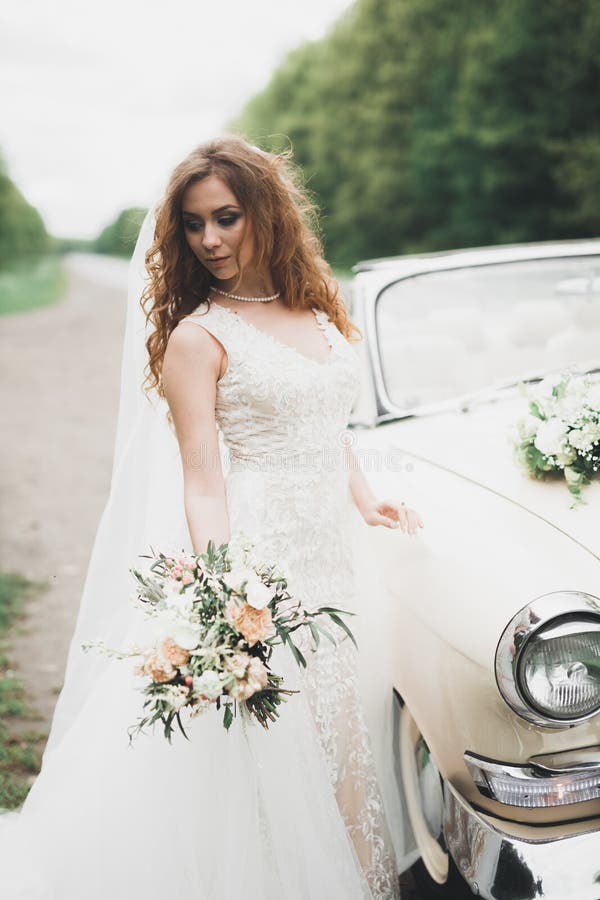 Happy bride in the retro car posing on her weeding day.