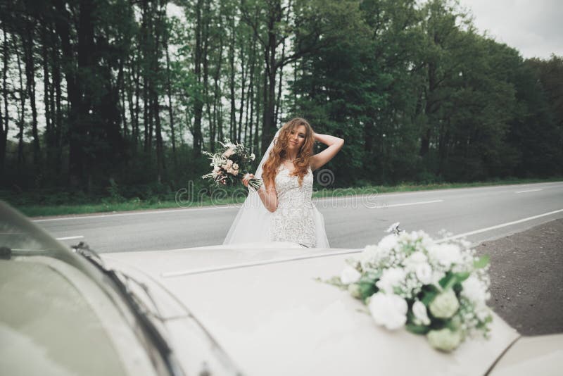 Happy bride in the retro car posing on her weeding day.