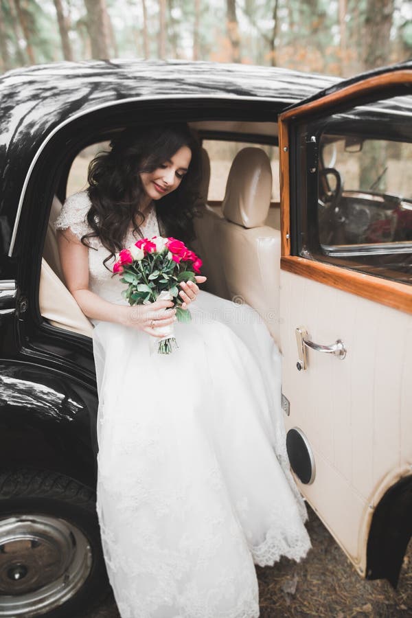 Happy bride in the retro car posing on her weeding day.