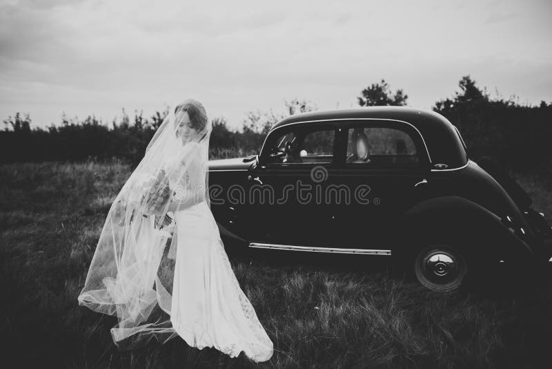 Happy bride in the retro car posing on her weeding day.