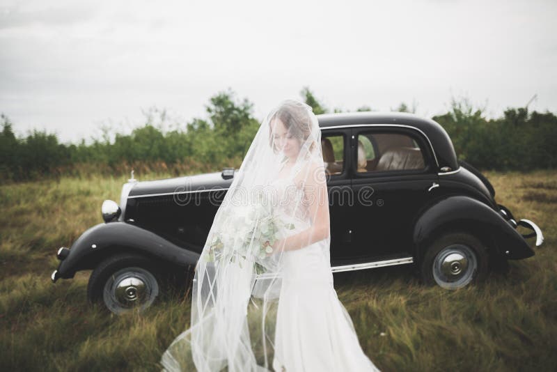 Happy bride in the retro car posing on her weeding day.