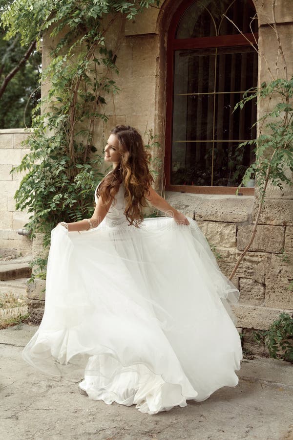 Happy bride woman running in wedding dress at park, outdoors portrait