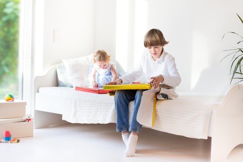 Happy brother and baby sister opening their presents on a sunny room