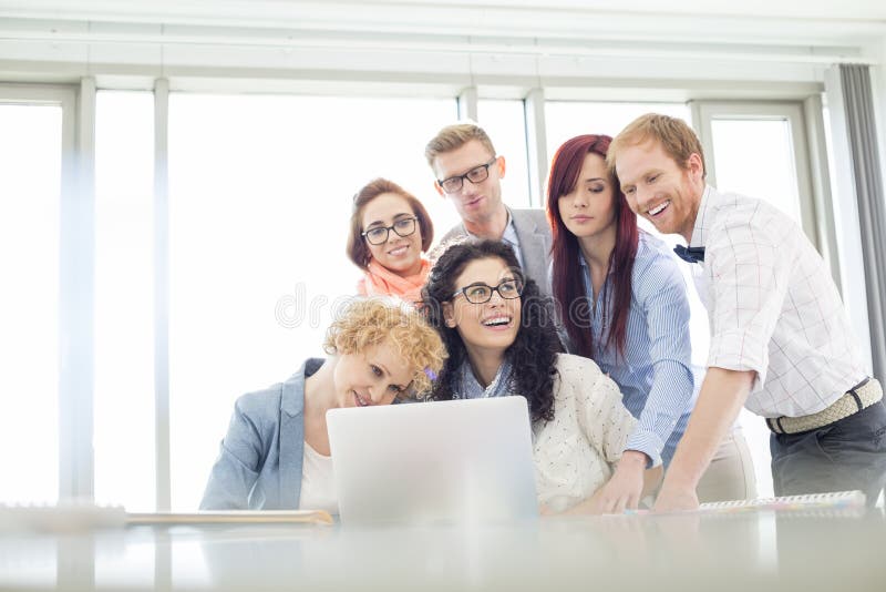 Happy business colleagues with laptop discussing in creative office stock images Happy business colleagues with laptop discussing in creative office stock images