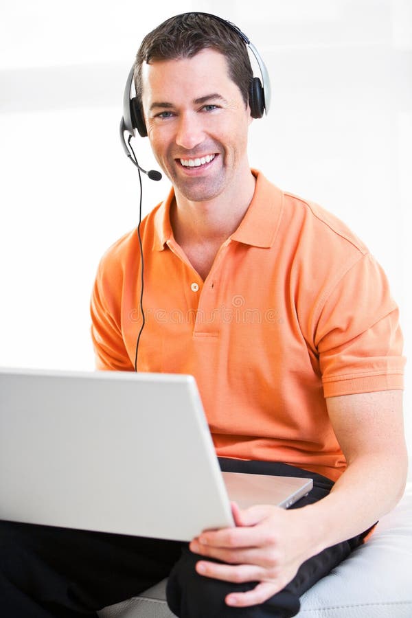 Happy business male on laptop with headset on smiling.