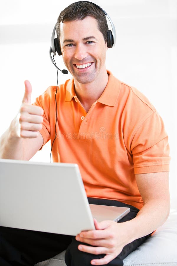 Happy business male on laptop with headset on smiling giving the thumbs up.