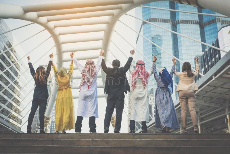 Happy business team making high hands in city background.