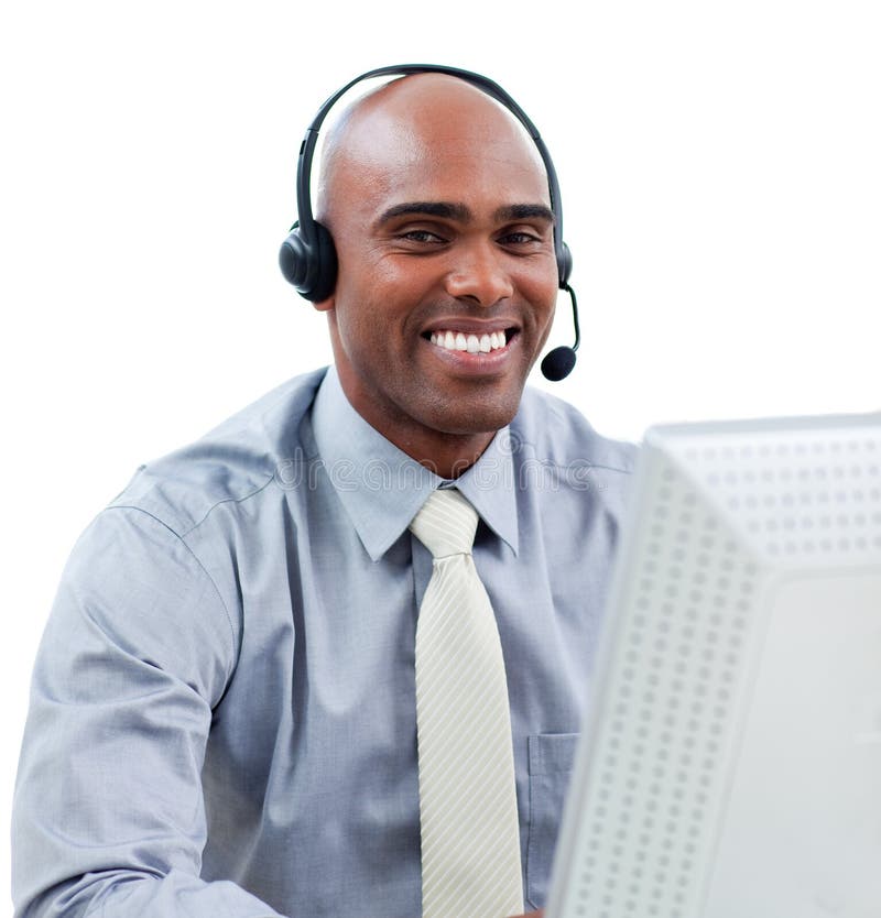 Happy businessman talking on headset at a computer in the office