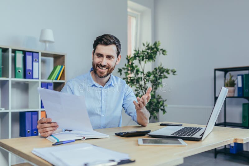 Happy businessman working with papers, working on laptop, man at work in a bright office royalty free stock photo