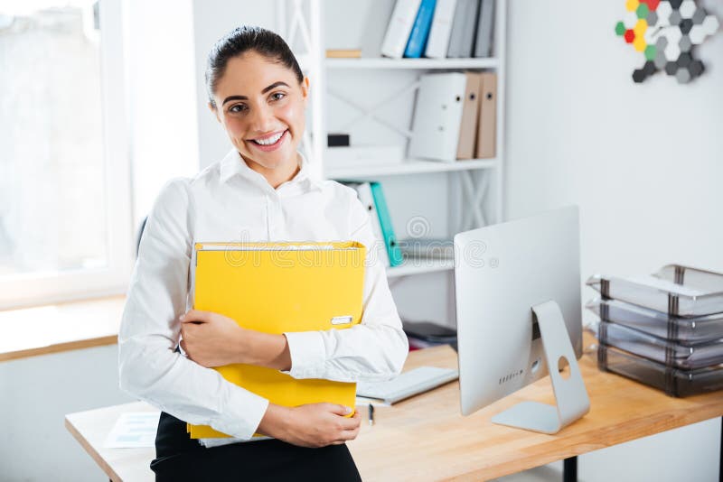 Happy businesswoman sitting on the table with documents in office. Analytic, horizontal.