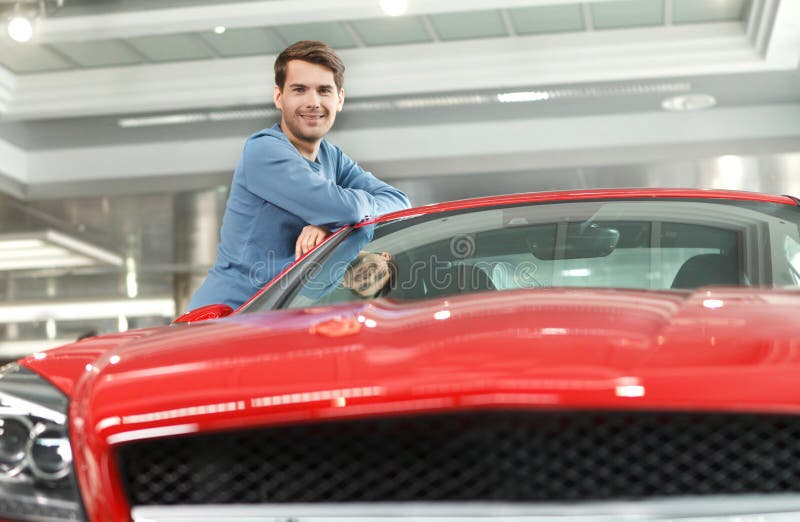 Happy car ownner. Handsome young men leaning on his new car at t stock photo Happy car ownner. Handsome young men leaning on his new car at t stock photo