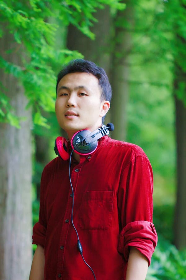 Happy careless free Asian Chinese man is listening to music and wearing a earphone