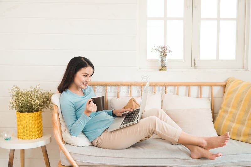 Happy casual beautiful asian young woman working on a laptop at