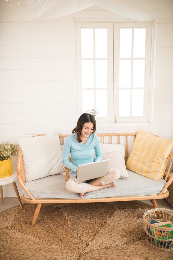 Happy casual beautiful asian young woman working on a laptop at