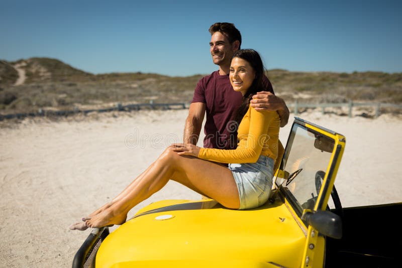 Happy Caucasian Couple Man Embracing Woman Sitting On Beach Buggy By The Sea Stock Image