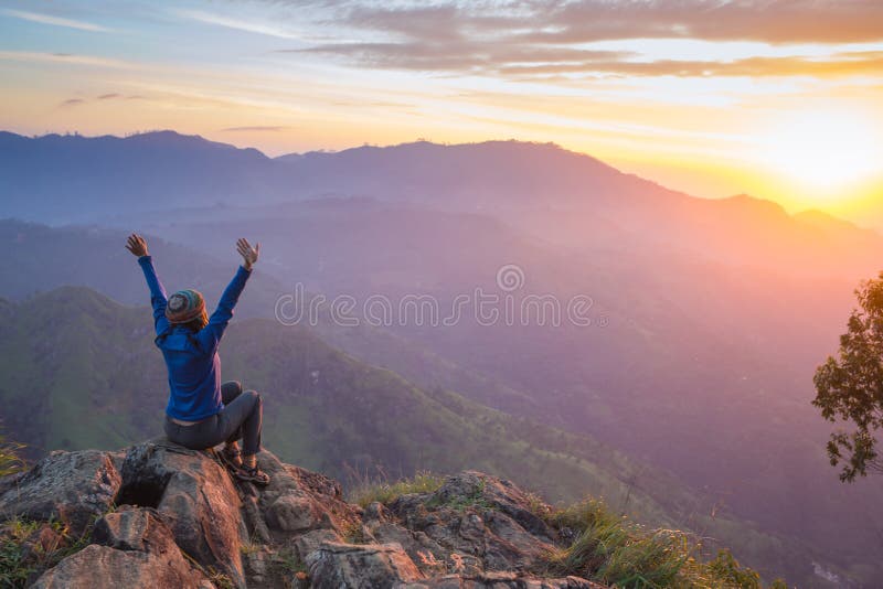 Rádi slaví vítězný úspěch žena při západu slunce nebo východ slunce stojí v povznesené náladě, s rukama zvedl nad hlavu na oslavu, které dosáhly vrcholu hory summit cíl během pěší turistika cestování trek.
