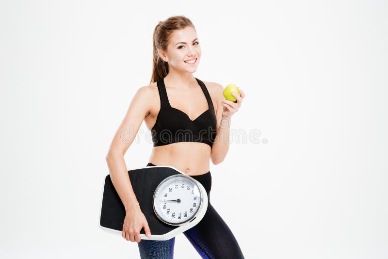 Happy cheerful fitness woman holding weight scales and green apple stock photography Happy cheerful fitness woman holding weight scales and green apple stock photography