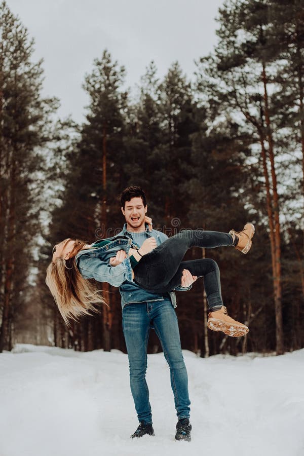 Happy cheerful smiling couple of young people in denim suits in snowy forest in winter . place for text. winter holiday