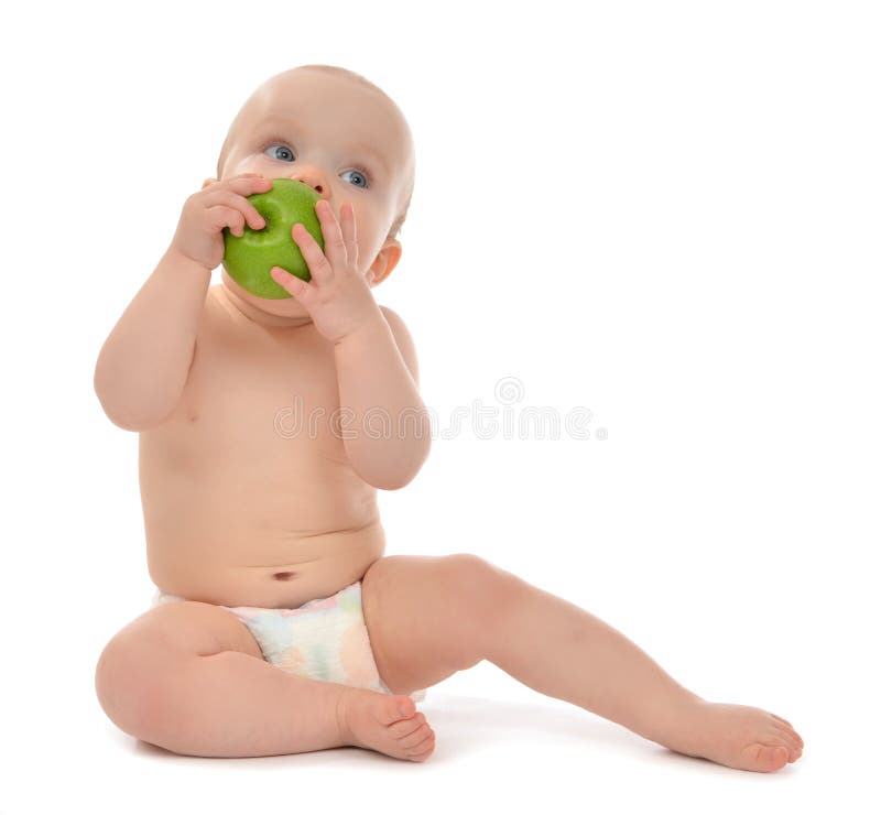 Happy child baby boy sitting in diaper and eating green apple