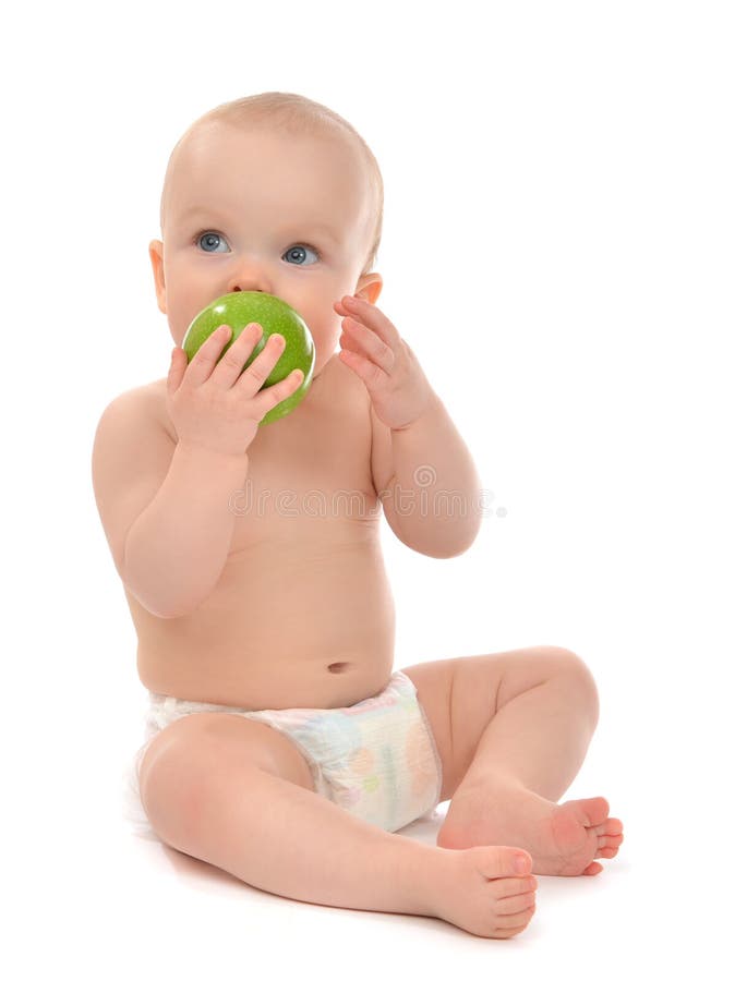 Happy child baby boy sitting in diaper and eating green apple