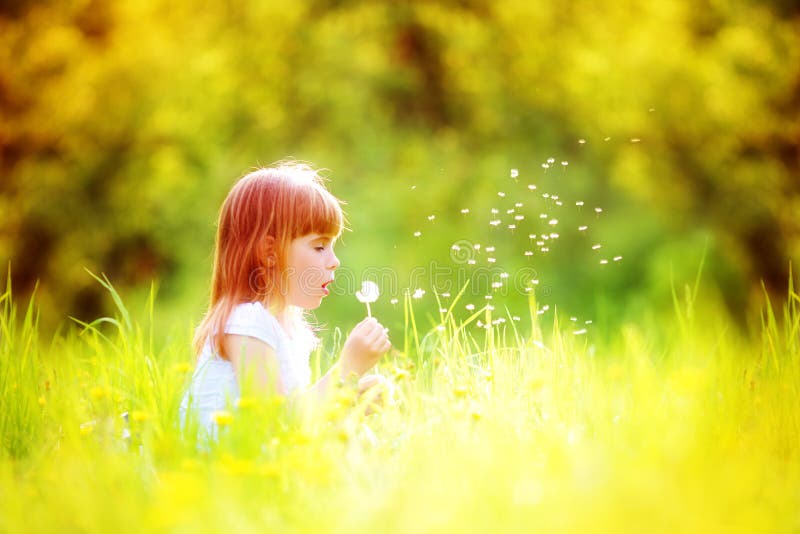 Happy child blowing dandelion outdoors in spring park