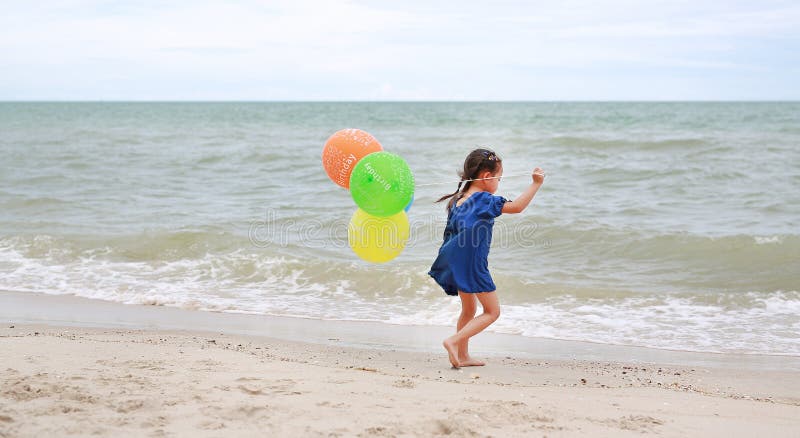Happy child with colorful balloons running on the beach stock photography Happy child with colorful balloons running on the beach stock photography