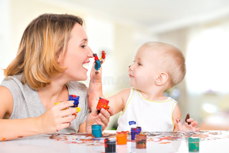 Happy child draws on the face of his mother.