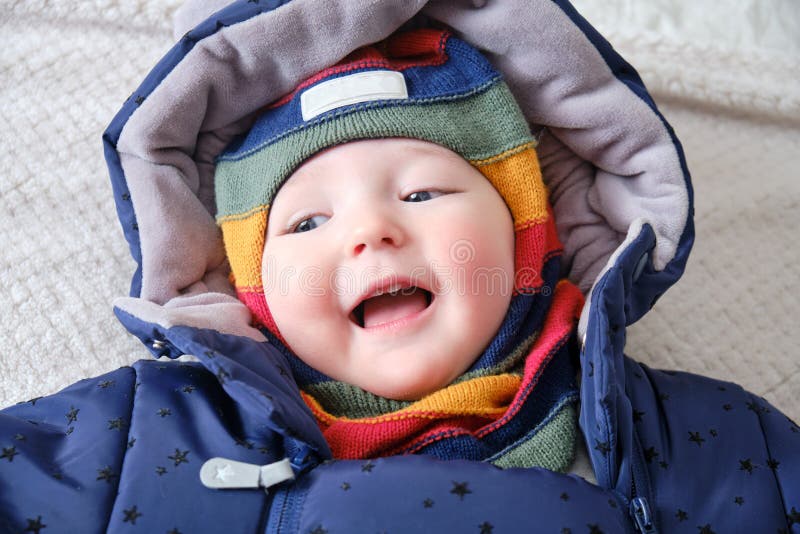 A Happy Child Dressed in Warm Winter Clothes is Lying on the Bed Stock