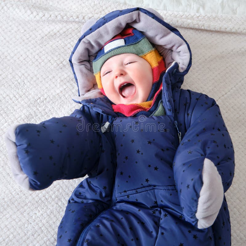A Happy Child Dressed in Warm Winter Clothes is Lying on the Bed Stock