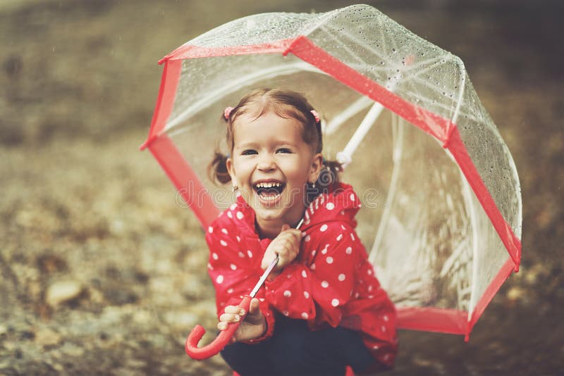 Happy child girl laughing with an umbrella in rain. Playing, nature.