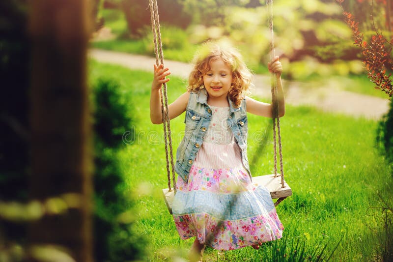 Happy child girl relaxing on swing in spring garden stock image Happy child girl relaxing on swing in spring garden stock image