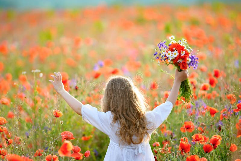 Happy child girl with wild field flowers running thru meadow in