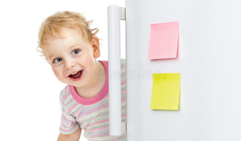 Happy child hiding behind fridge door