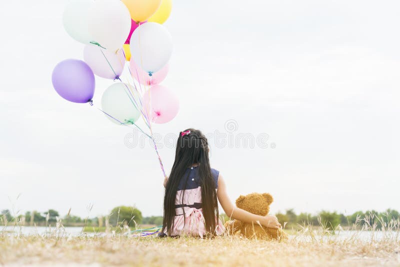Happy Child hug teddy bear hold air balloon in green park playground. Teddy bear best friend for little kids cute girl. Autism stock photos Happy Child hug teddy bear hold air balloon in green park playground. Teddy bear best friend for little kids cute girl. Autism stock photos