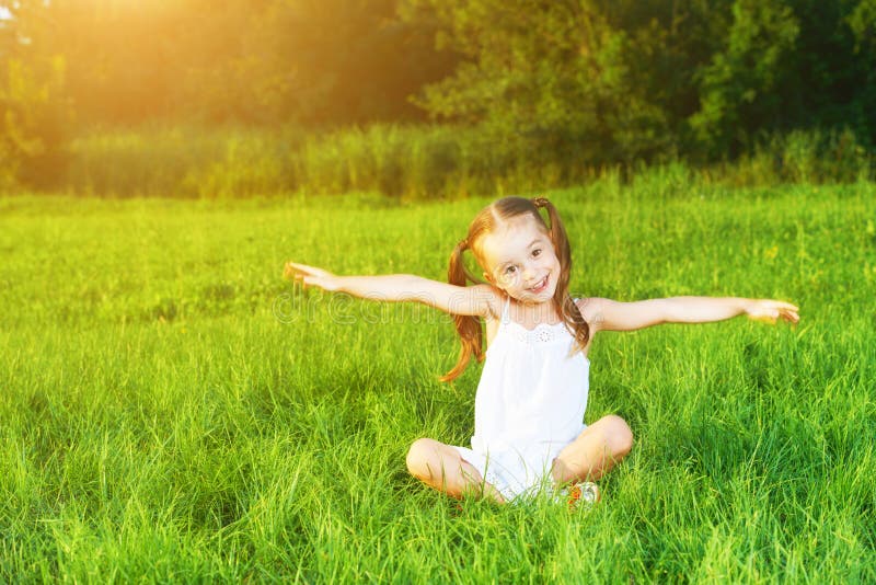 Happy child little girl spread his arms in white dress lying on stock image Happy child little girl spread his arms in white dress lying on stock image