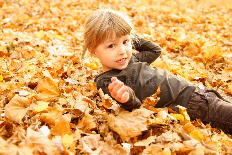 Happy child playing on the autumn leaves in nature
