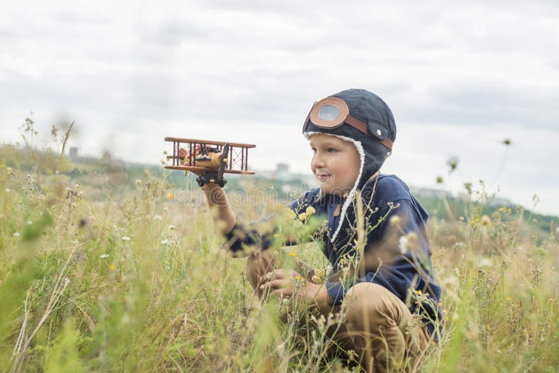 Happy child playing with a toy wooden plane outdoors. Little boy with wooden plane