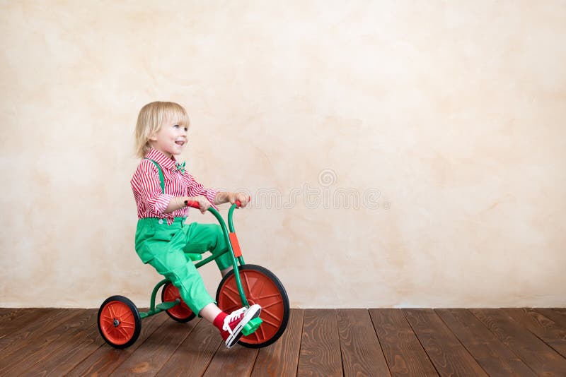Happy child riding vintage tricycle. Kid having fun at home. Imagination and childhood concept