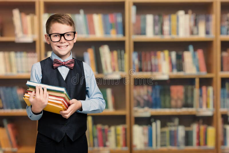 Happy Child in School Library Holding Books, Well Dressed Pupil Boy Portrait, Smiling Kid in Glasses over Bookshelves. Happy Child in School Library Holding Books, Well Dressed Pupil Boy Portrait, Smiling Kid in Glasses over Bookshelves