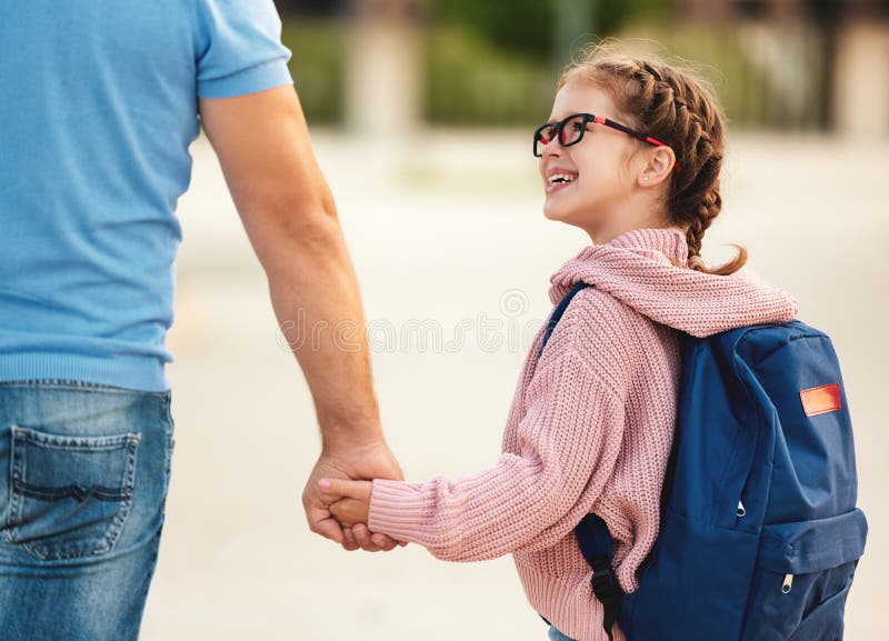 First day at school. father leads  little child girl in grade