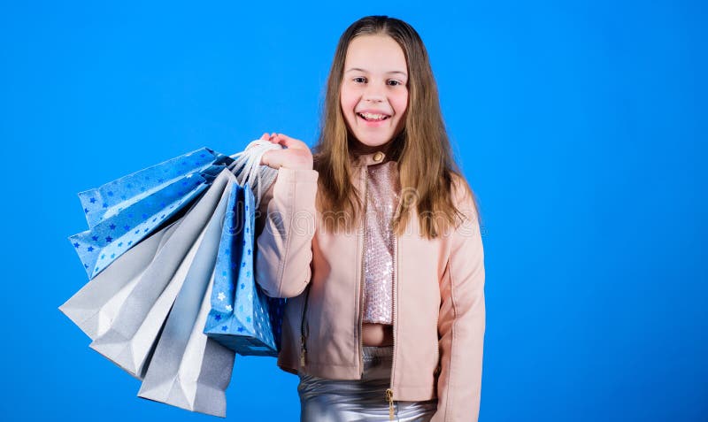 Happy child in shop with bags. Shopping day happiness. Buy clothes. Fashionista addicted buyer. Fashion boutique kids royalty free stock photography Happy child in shop with bags. Shopping day happiness. Buy clothes. Fashionista addicted buyer. Fashion boutique kids royalty free stock photography