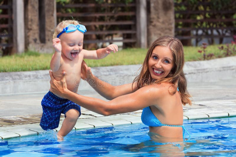 Happy child swim with beautiful woman in pool