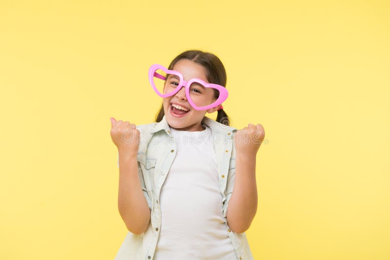 Happy child wear heart shaped glasses on yellow background. Little girl smile in fashion accessory. Funky style beauty royalty free stock image Happy child wear heart shaped glasses on yellow background. Little girl smile in fashion accessory. Funky style beauty royalty free stock image