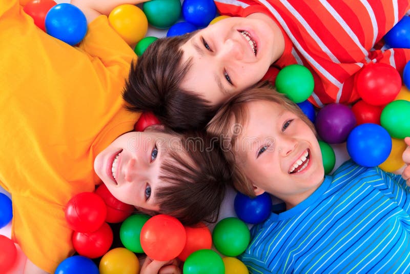 Bambini felici compreso fra colorate palline di plastica.
