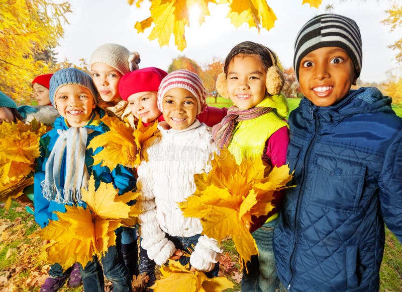 Happy children with bunches of yellow maple leaves