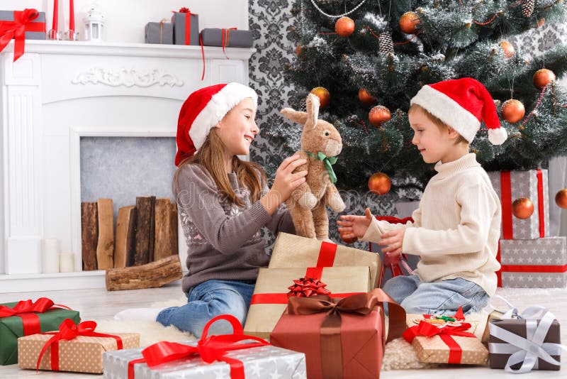 Happy children in santa hats unwrapping christmas presents stock image Happy children in santa hats unwrapping christmas presents stock image