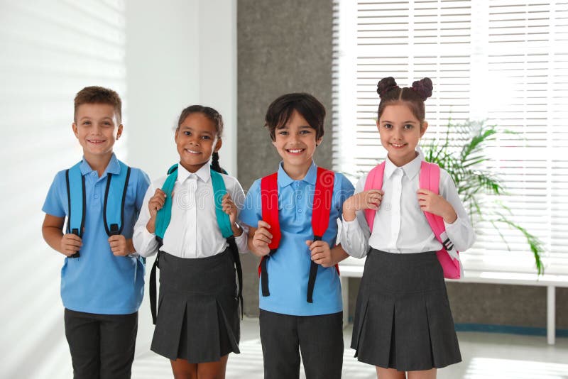 Happy children in school uniform with backpacks. Indoors